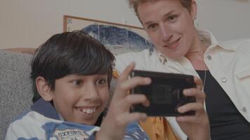 vrouw kijken jongen met gameconsole op Bank video