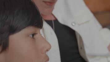 Boy playing with game console and woman watching on couch video