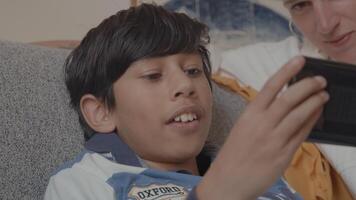 Boy playing with game console and woman watching on couch video