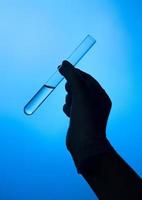 Hand with a protective glove holding a medical tube photo