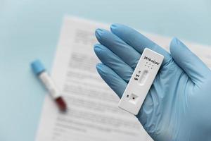 Hand with protective gloves holding covid test photo