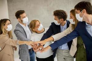 Masked team putting hands together looking at each other photo