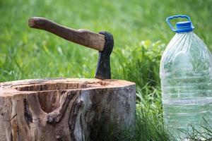 Ax in a wooden stump and a jar of water photo