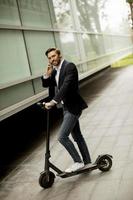Hombre montando scooter mientras habla por teléfono foto