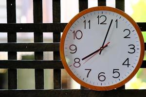 Reloj de pared sobre fondo de madera y concepto de tiempo foto