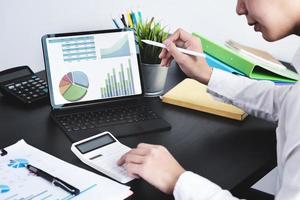 The young businessman  using tablet computer and calculators  to check financial statements at home instead of working in the office photo