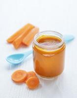 zanahoria baby triturada con cuchara en frasco de vidrio foto