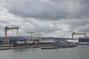 Grandes grúas industriales cargando un buque portacontenedores en el puerto de Belfast en Irlanda foto