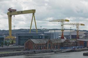 Grandes grúas industriales cargando un buque portacontenedores en el puerto de Belfast en Irlanda foto