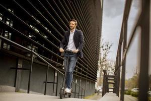 Businessman riding a scooter near a building photo