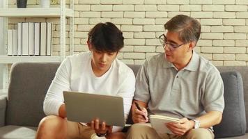 pai e filho asiáticos trabalhando em um laptop video
