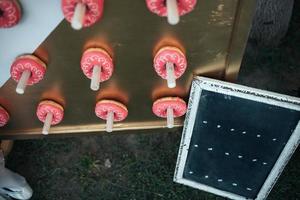 Stand with donuts pink in nature with a small table for text photo