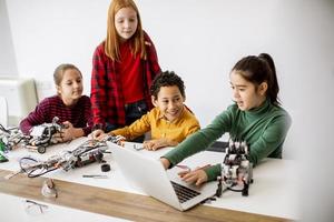 Niños felices programando juguetes eléctricos y robots en el aula de robótica foto