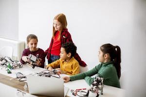 Niños felices programando juguetes eléctricos y robots en el aula de robótica foto