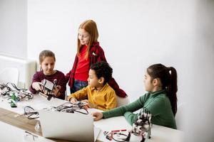 Happy kids programming electric toys and robots at robotics classroom photo