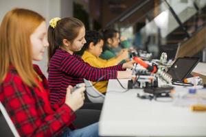Happy kids programming electric toys and robots at robotics classroom photo