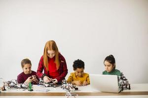 Happy kids programming electric toys and robots at robotics classroom photo