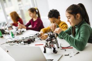 Happy kids programming electric toys and robots at robotics classroom photo