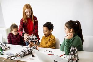 Niños felices programando juguetes eléctricos y robots en el aula de robótica foto