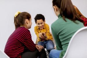 Portrait of cute little kids in jeans  talking and sitting in chairs against white wall photo