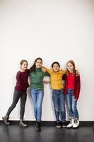 Portrait of cute little kids in jeans looking at camera and smiling standing against white wall photo