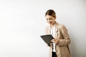 Mujer joven sosteniendo tableta digital por la pared blanca en la oficina moderna foto