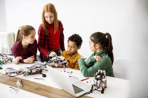 Happy kids programming electric toys and robots at robotics classroom photo