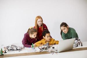 Happy kids programming electric toys and robots at robotics classroom photo