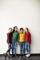 Portrait of cute little kids in jeans looking at camera and smiling standing against white wall photo