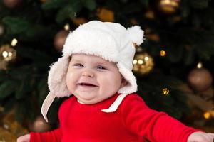 A cute little girl in a red dress and white hat expresses emotions photo