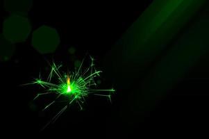 Sparkler in green and white light on a black background photo