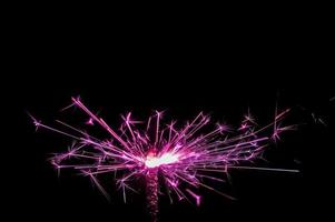 Sparkler in pink and white light on a black background photo