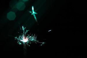 Sparkler in turquoise and white light on a black background photo