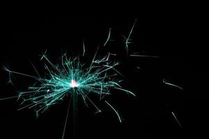 Sparkler in turquoise and white light on a black background photo