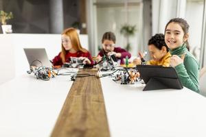 Niños felices programando juguetes eléctricos y robots en el aula de robótica foto