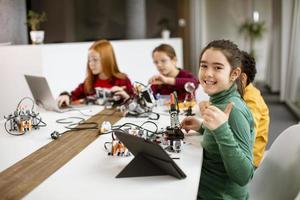 Niños felices programando juguetes eléctricos y robots en el aula de robótica foto