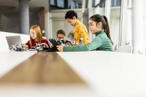 Happy kids programming electric toys and robots at robotics classroom photo