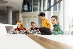 Happy kids programming electric toys and robots at robotics classroom photo