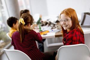 Niños felices programando juguetes eléctricos y robots en el aula de robótica foto