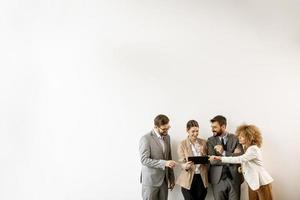 Gente de negocios multiétnica con tableta digital mientras está de pie junto a la pared en la oficina foto