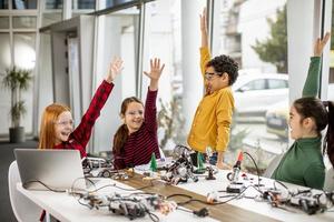 Happy kids programming electric toys and robots at robotics classroom photo