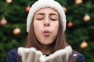 Christmas beautiful woman blowing a kiss at you against christmas tree background photo