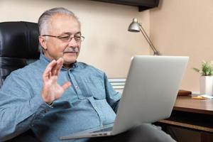 Old man makes video call talking with relatives or friends by video conference app photo