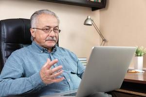 Old man makes video call talking with relatives or friends by video conference app photo