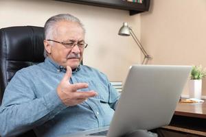 Old man makes video call talking with relatives or friends by video conference app photo