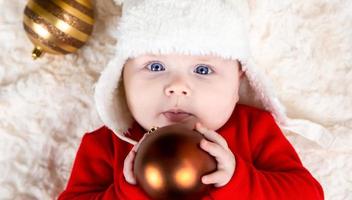 Cute baby biting xmas ball lying on the floor photo