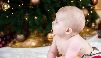 Bebé desnudo en el suelo de la sala de Navidad decorada. foto