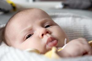 A close-up portrait of a newborn baby girl who drooling photo