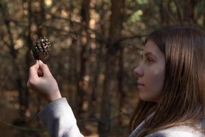 Girl holds a pinecone in her hands photo