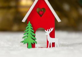 Christmas wooden toy house deer and tree on a white blanket imitating snow photo